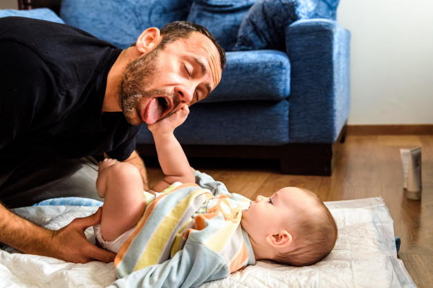 father-making-funny-gestures-his-baby-daughter-while-changing-his-diaper_47726-7754-f31065ff