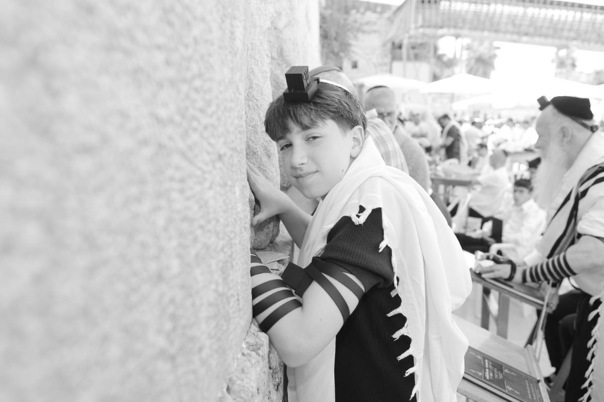 משפחה חוגגת בר מצווה חגיגית עם מתופפים ופייטן ברחבת הכותל